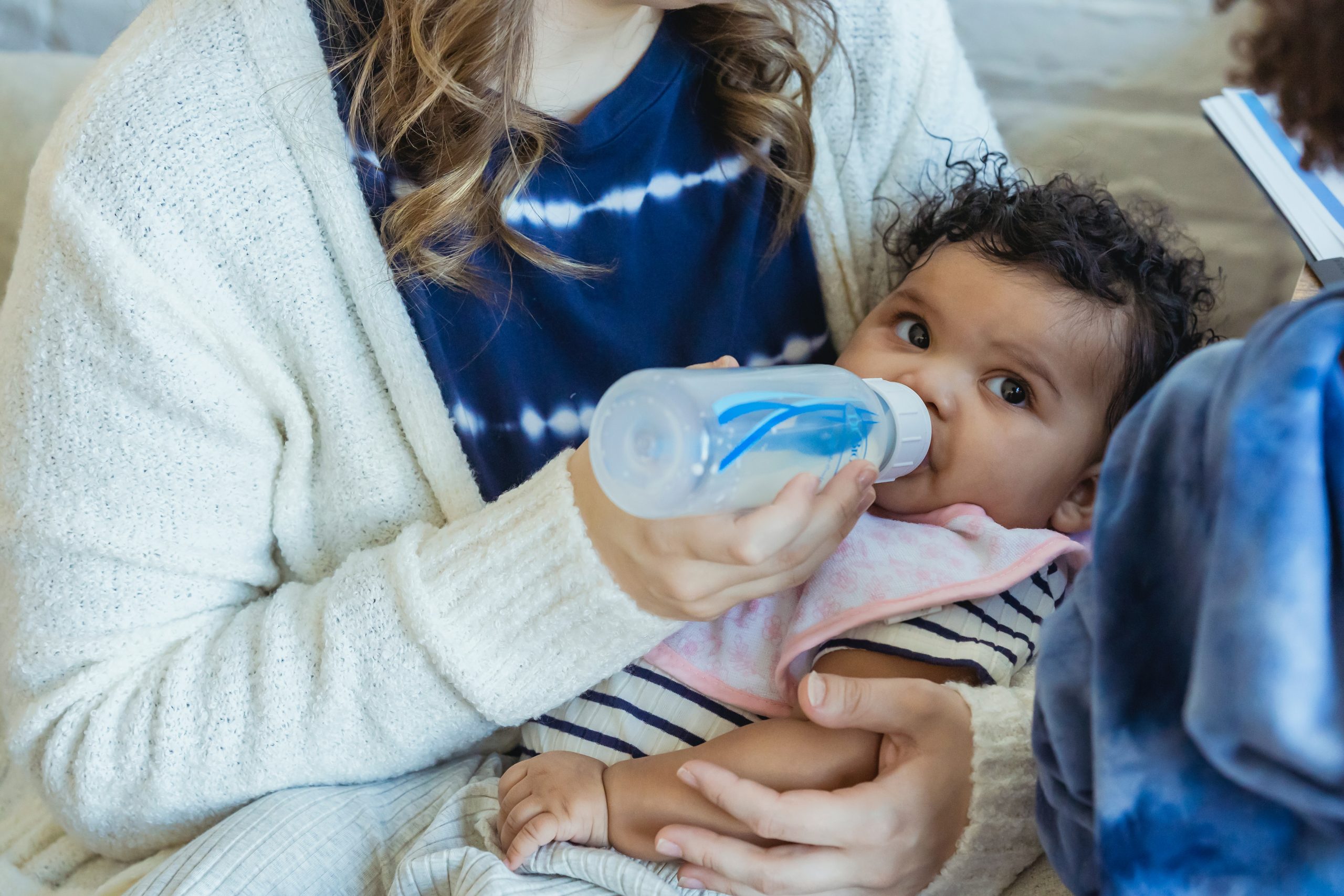 A mother feeding a baby using a bottle.