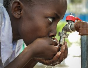 a child drinking water from a tap
