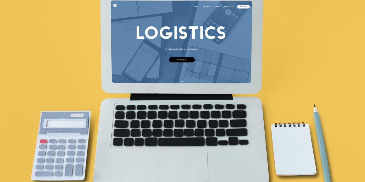 a laptop, calculator, a notepad and a pen to illustrate the concept of logistics and procurement