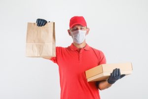 Food delivery man handling food in medical mask and gloves