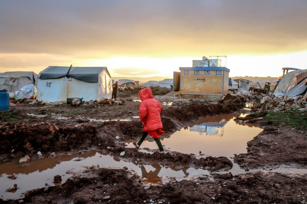 A little girl walking on mud in a displacement camp