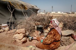 An elderly woman cooking in a refugee camp