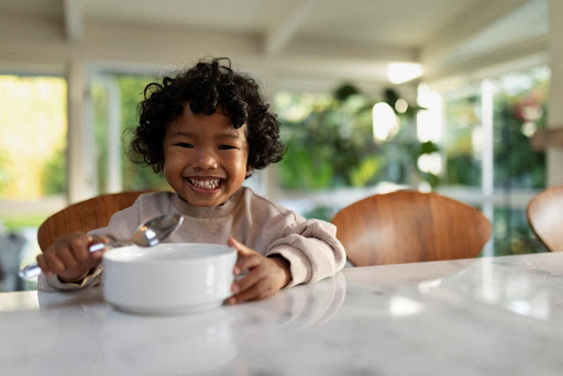 a smiling baby with a plate and a spoon